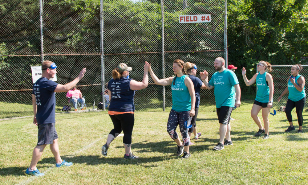 Photo to two BeepBall teams lined up giving high fives after a game