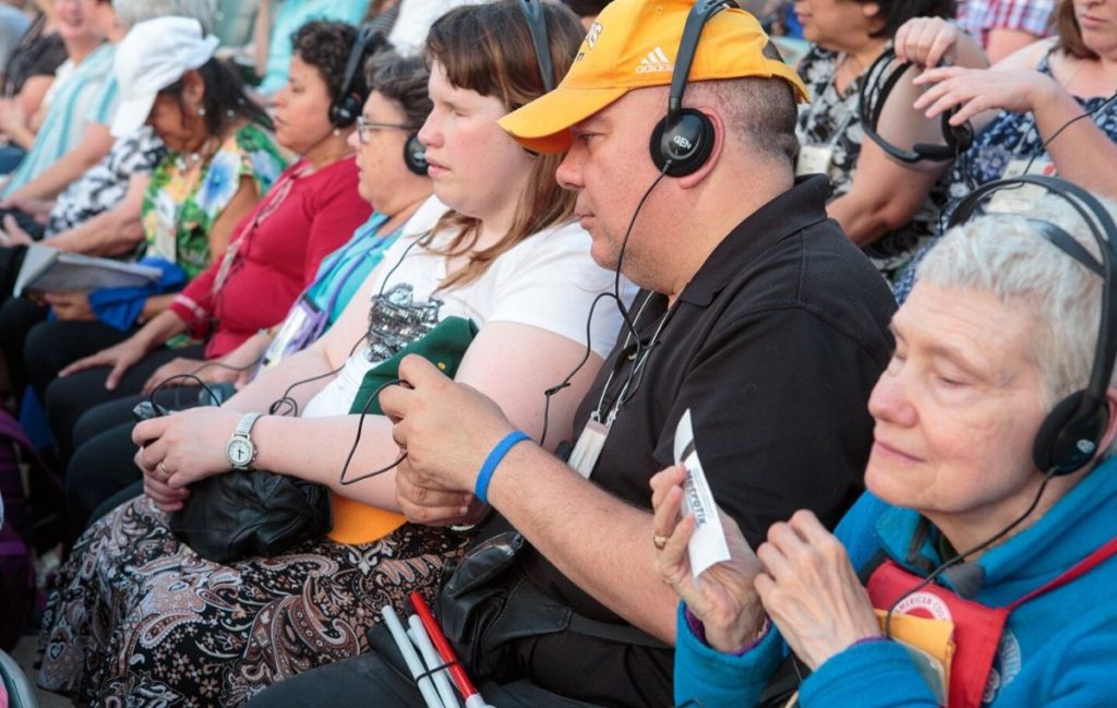 A group of Audio Description patrons at the Muny wearing headphones