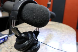 Headphones dangle over a microphone in the recording studio.
