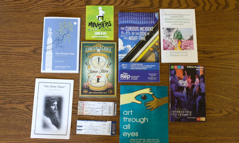 A display of Musical and Theatre Production Programs laid out on a wooden table