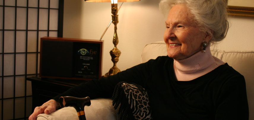 A woman with gray hair sits in front of a radio