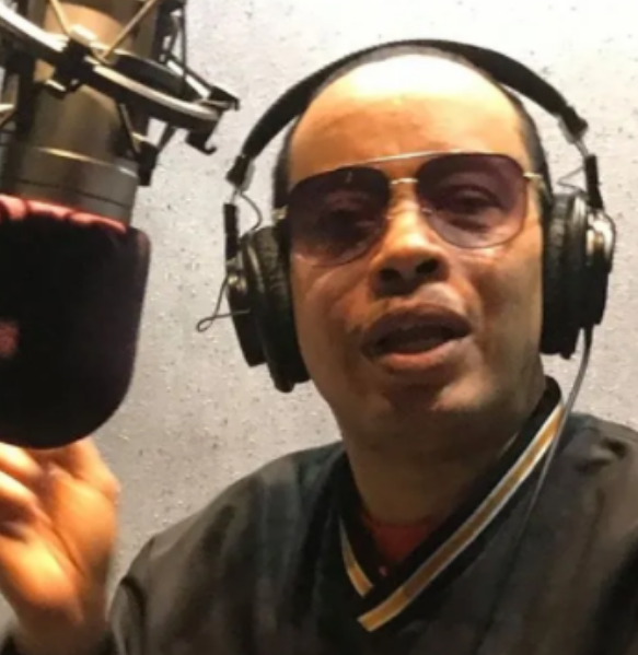 Photo of Langford Cunningham wearing headphones and speaking in to a studio microphone.
