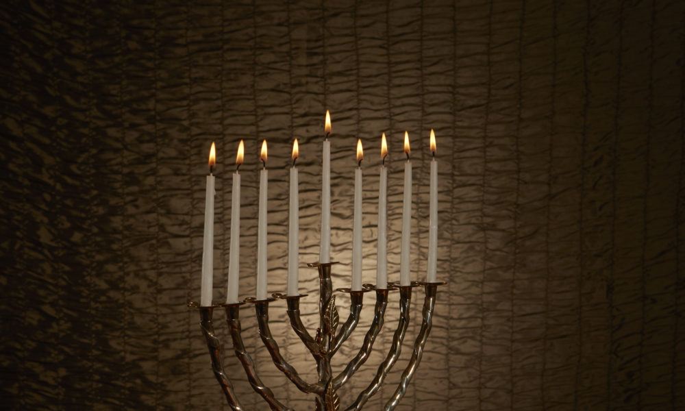 A Menorah with lit white candles on a table
