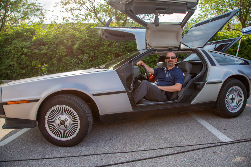 Chad Dillon sits inside a Delorean with both gullwing doors open