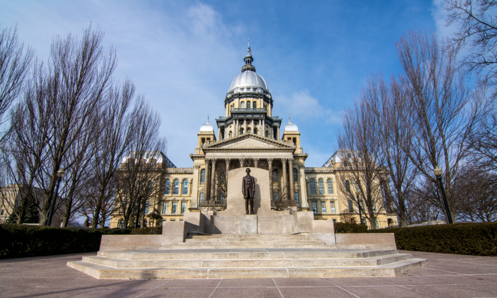 The Springfield state capitol building, with columns and domed roof, behind a statue of Abraham Lincoln.
