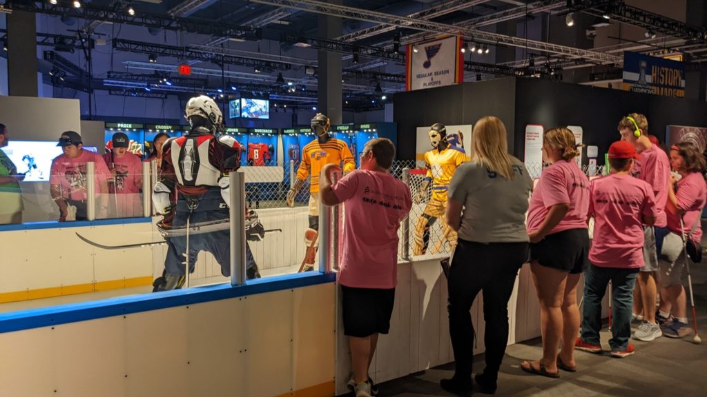 A group of people look at a hockey exhibit at the St. Louis Science Center.