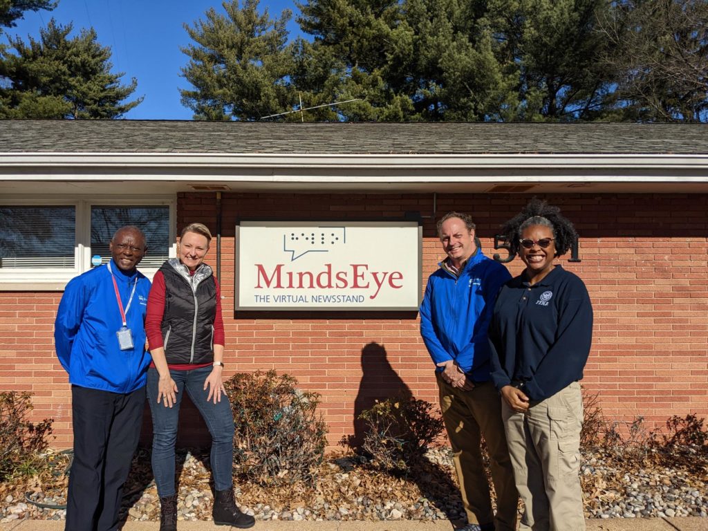 Photo: LeRoy, Laura, Matt, and Tiana smile in front of the MindsEye studio sign.