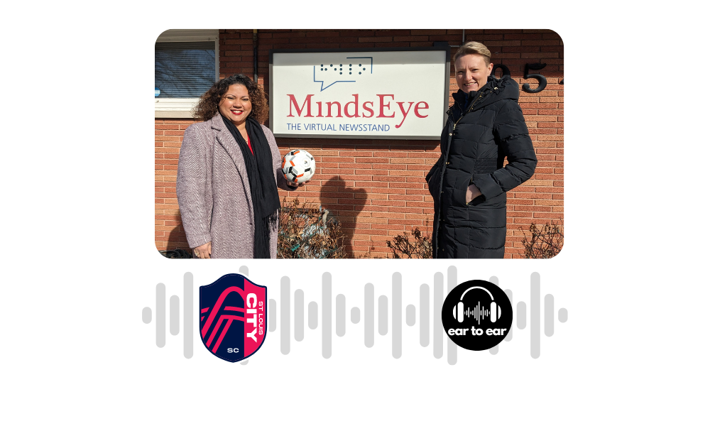 Barbra, holding a blind soccer ball, stands in front of the MindsEye studio sign with Laura.